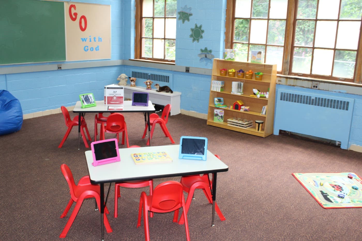 A Champions Club classroom at Impact City Church with tablets, learning stations, and a GO with God wall