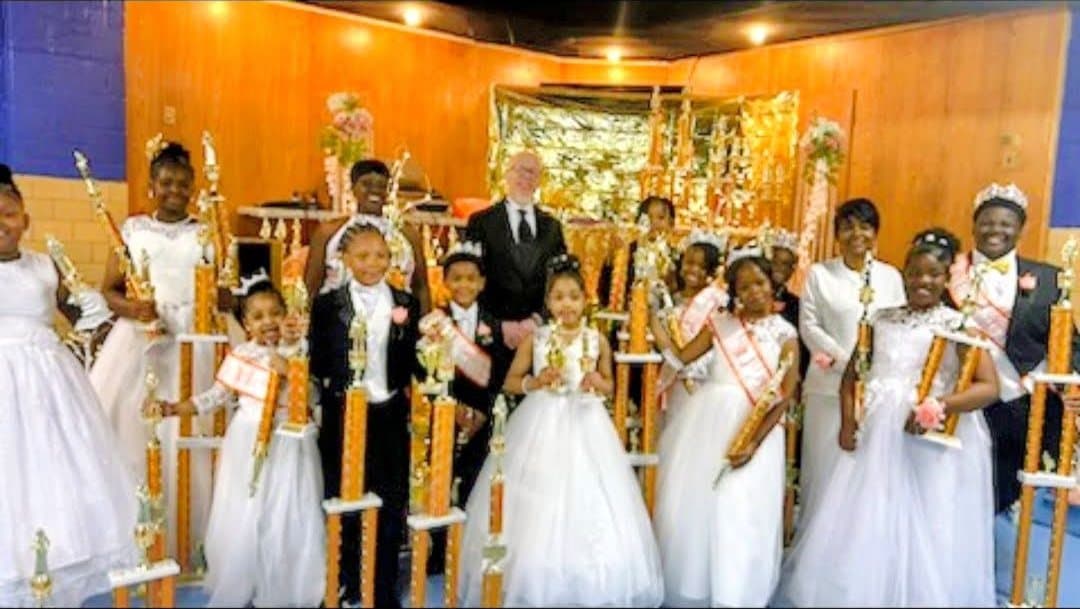 Cotillion participants in crowns and sashes holding their trophies
