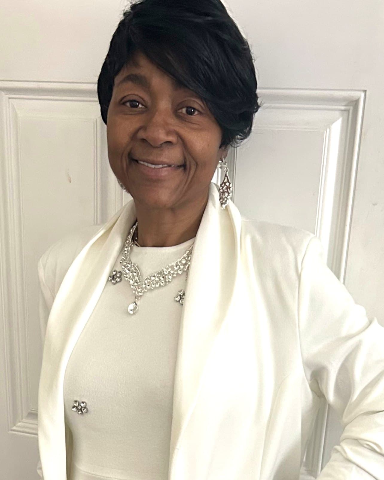 Elder Shira Dunson in a white suit and crystal necklace