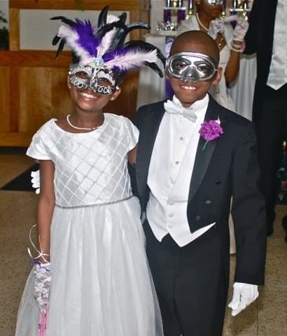A young lady and young gentleman in masquerade masks, smiling
