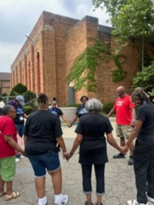 A prayer circle with joined hands outside the church building