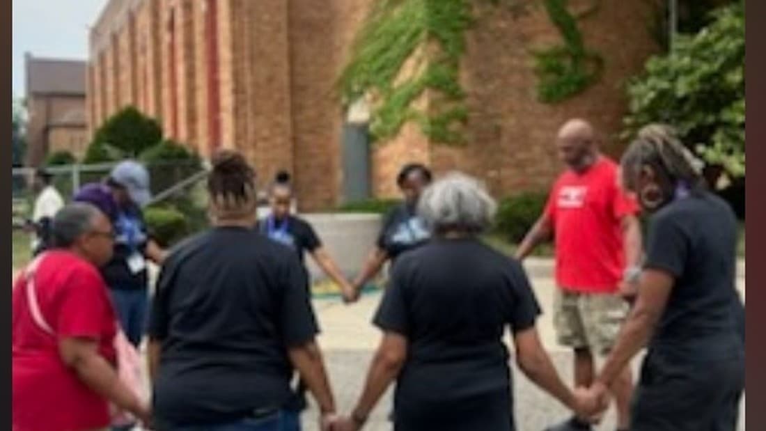 Impact City members in a prayer circle outside the church, hands joined