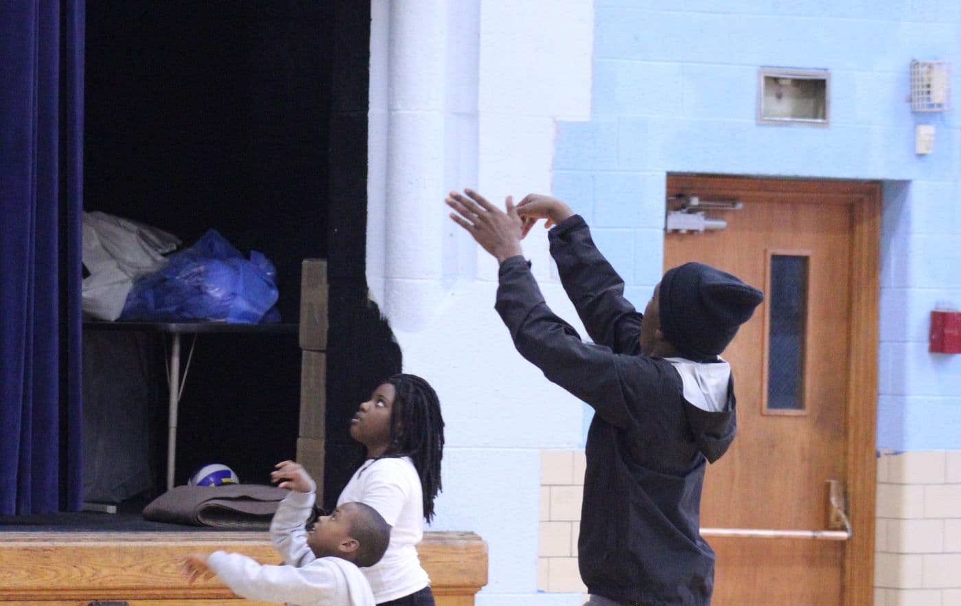 A student takes a jump shot in the gym