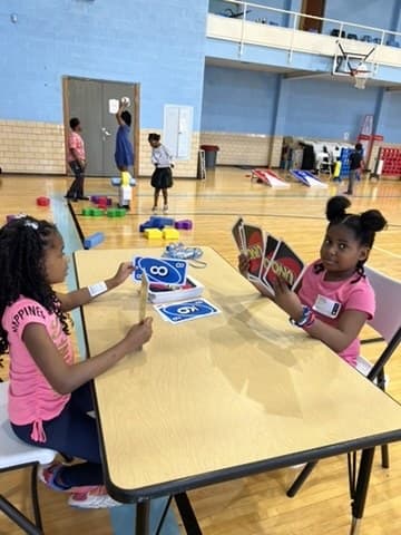 Two girls working through activity cards together at a table
