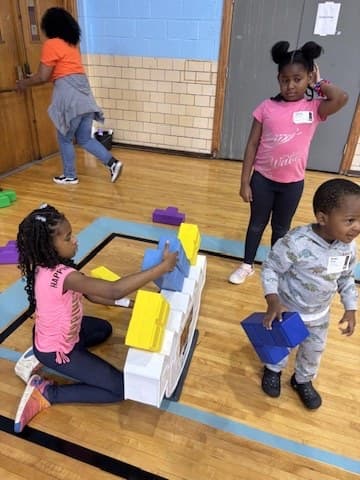 Children building a tower out of foam blocks in the gym