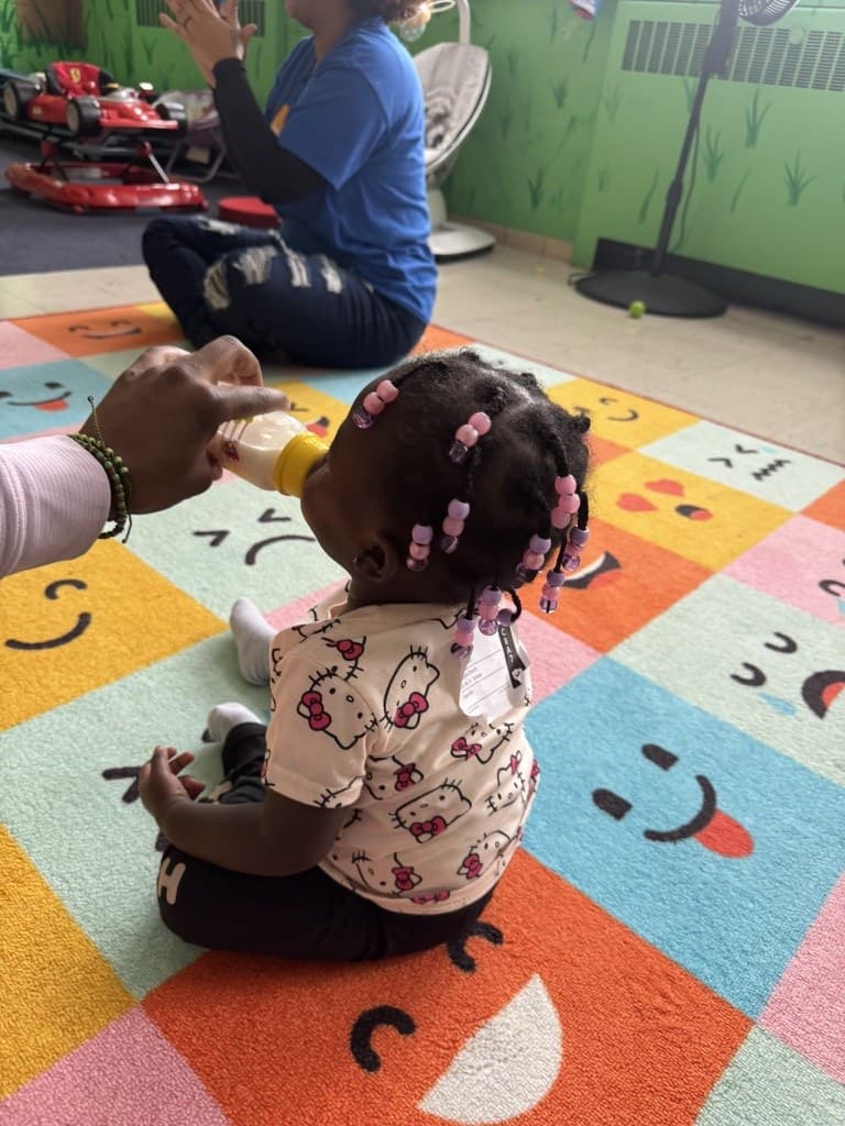 A leader kneeling beside a child on the classroom carpet