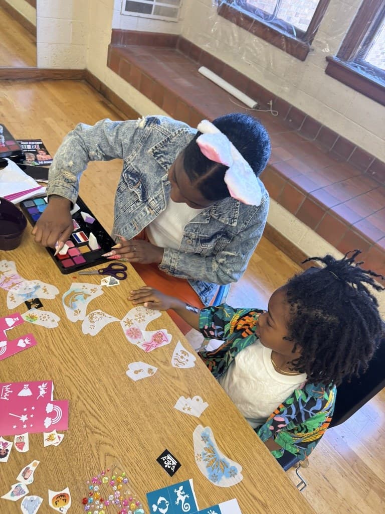 A leader working on a craft alongside a child at the table