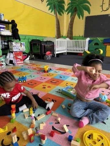 A child playing with wooden blocks on the classroom mat