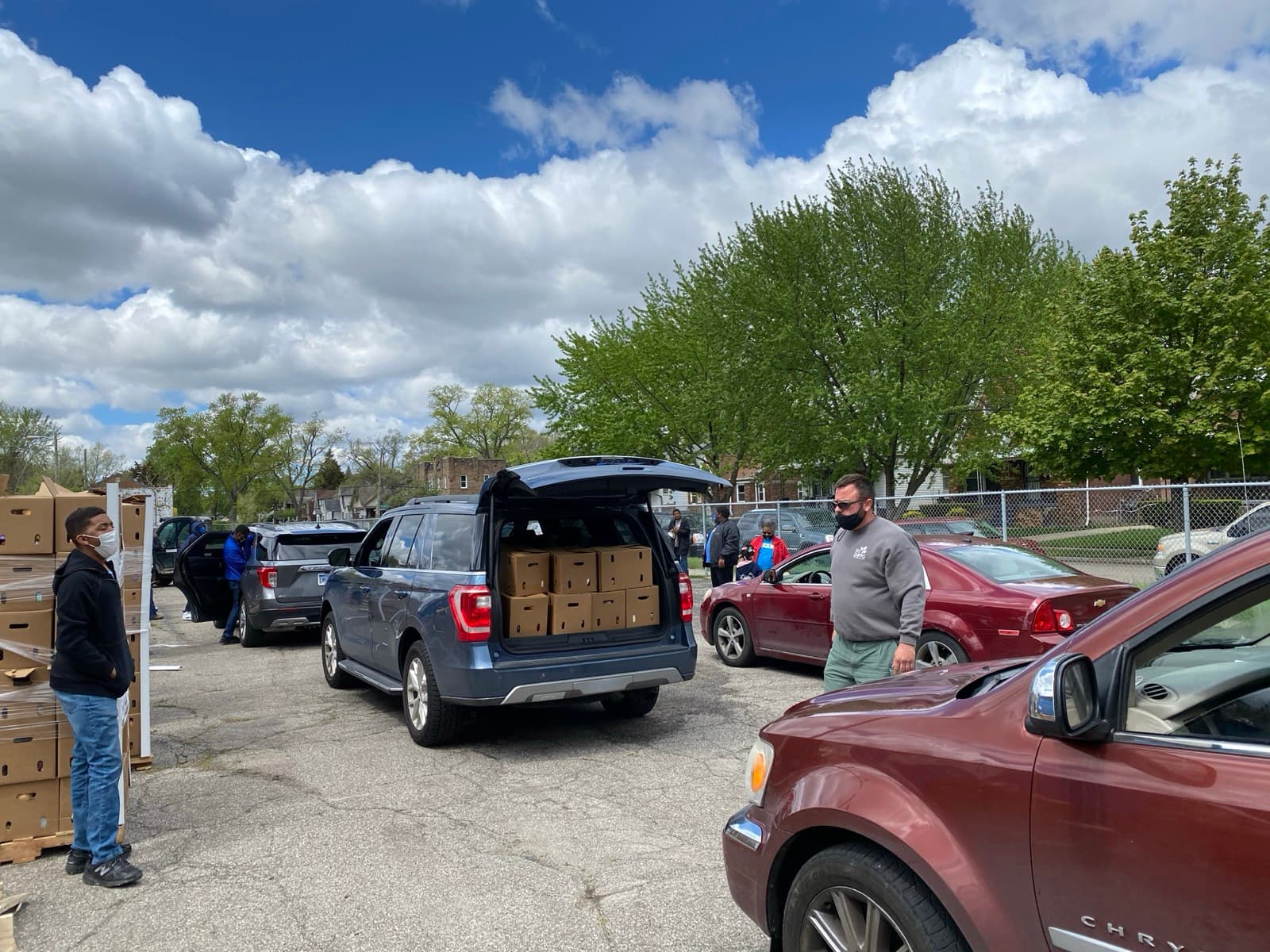 Masked Impact City Church volunteers loading boxes of food into a line of cars during the pandemic, May 2021