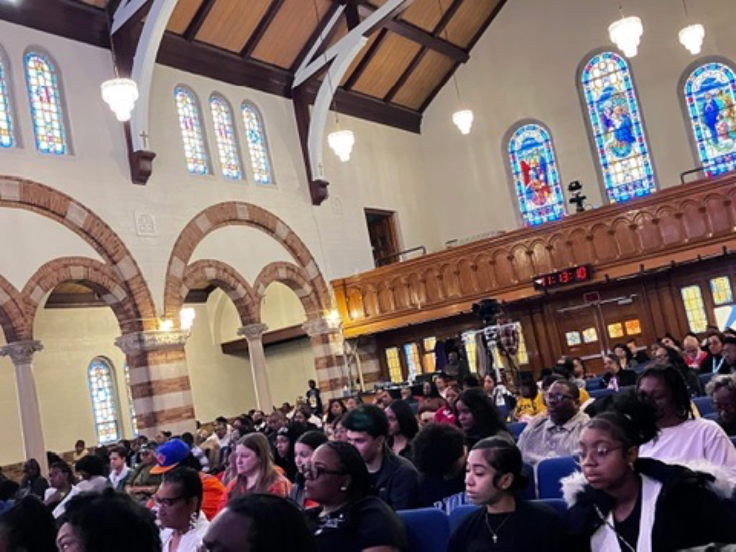 A full sanctuary at Impact City Church, congregation gathered under the stained-glass arches on a Sunday morning